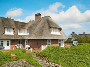 A traditional thatched-roof house with a brick facade, a front porch, and a stone staircase leading to the entrance. - Rasmus 1 from A&M - Rasmus 1 (Kampen (Sylt))