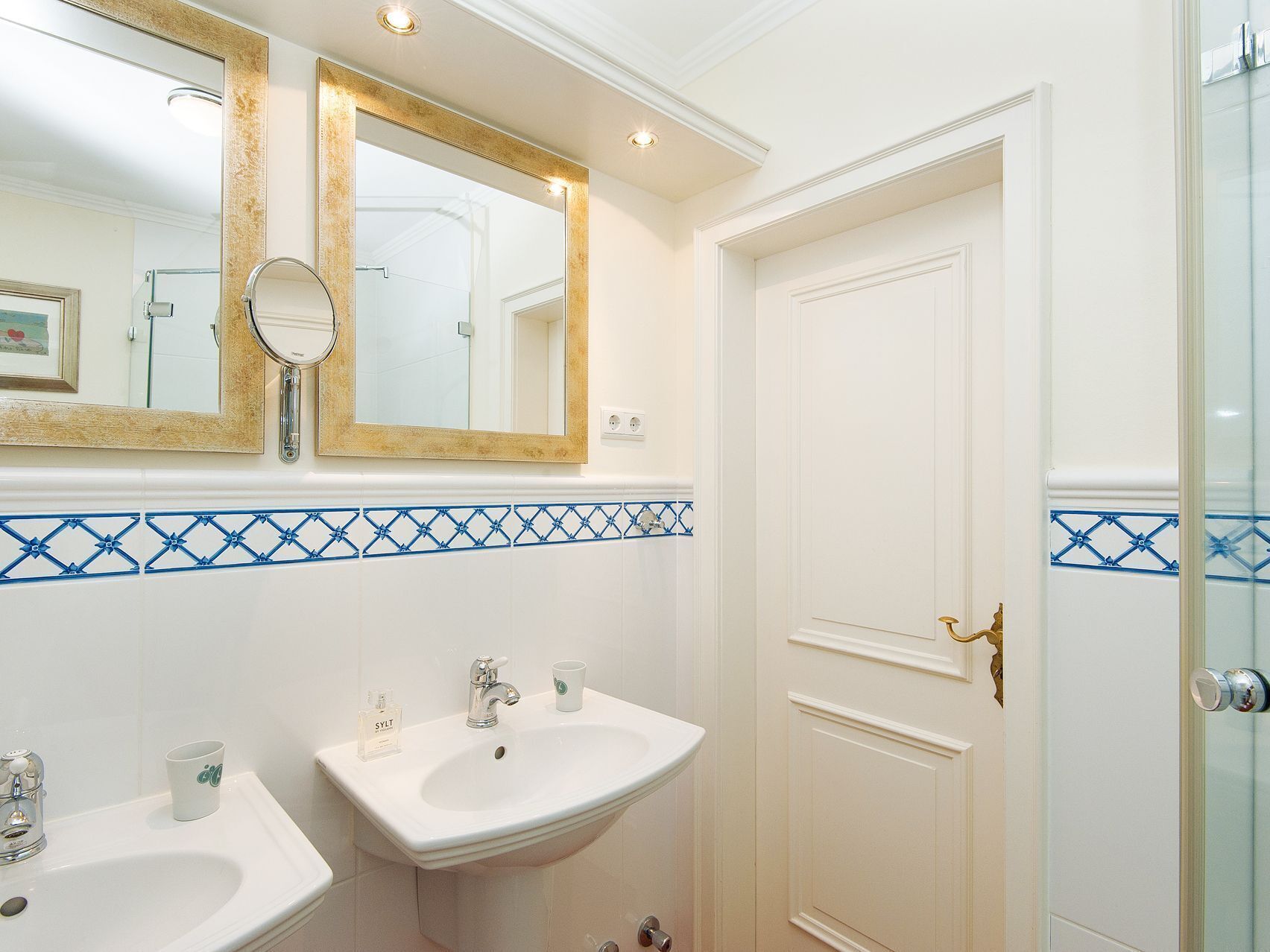 Een badkamer met twee wasbakken, een spiegel en een deur.
