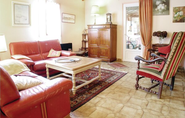A living room with a red leather sofa, a wooden coffee table, a striped armchair, and a cabinet.