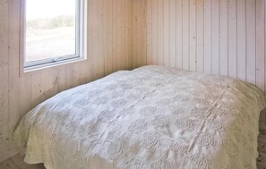 A room with a bed, wooden walls, and a window. - Nice home in Fjerritslev with sauna (Fjerritslev)
