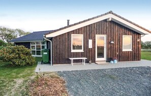 Una casa de madera con techo inclinado, un porche delantero y una pequeña mesa.