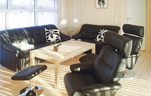 A modern living room with a black leather sofa, a wooden coffee table, and a black leather armchair. - Nice home in Fjerritslev with sauna (Fjerritslev)