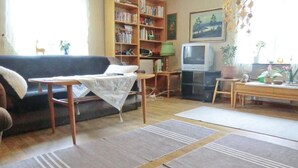 Ett vardagsrum med en soffa, en tv, en bokhylla och ett litet bord.