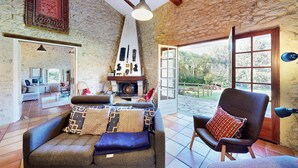Ein rustikales Interieur mit Steinwänden, einem Kamin und Blick ins Freie.