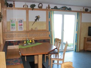 A dining area with a wooden table, chairs, a bench, and a decorative wall with framed pictures. - Margaritenwohnung - Bauernhof Schöbringer bed and breakfast (Miglberg)