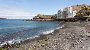 A coastal beach with rocky terrain and a clear view of the sea.