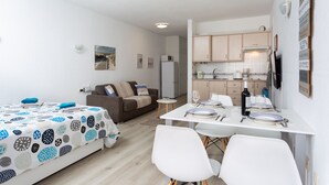 A compact living space with a kitchenette, a dining area, and a sofa.