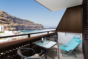 A balcony with a table and chairs overlooking a coastal view. - Studio Atlantic View II (Icod de los Vinos)