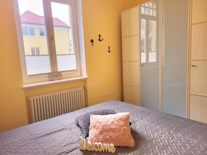 A bedroom with a bed, a window, a radiator, and a wardrobe.