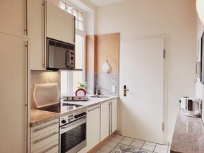 Una cocina compacta con microondas, estufa, pileta y una pequeña mesada.