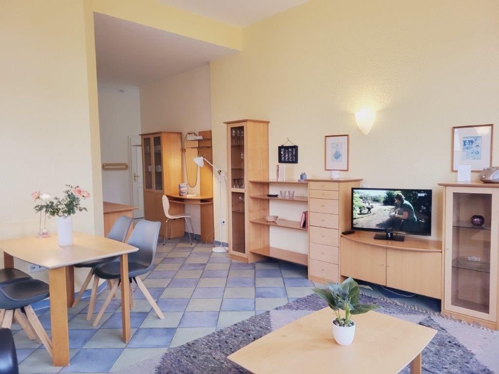 A compact living space with a dining area, a television, and a small bookshelf.
