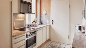 Une cuisine compacte équipée d’un four à micro-ondes, d’une cuisinière, d’un évier et d’un petit plan de travail.