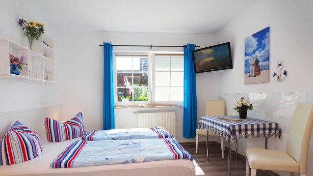 A hotel room with a bed, a desk, a chair, a TV, and a window with curtains.