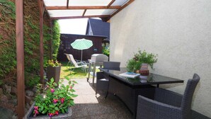An outdoor patio area with a table and chairs, a grill, and a potted plant.