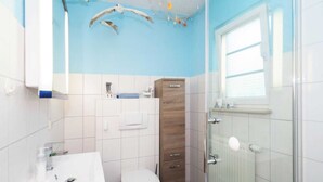 A bathroom with a white sink, a toilet, a wooden cabinet, and a glass shower enclosure.