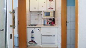 A compact kitchen with white cabinets, a microwave, and a small oven.