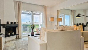 A modern living room with a sofa, a fireplace, a large window with curtains, and a view of the city. - El mirador de Calahonda (Calahonda)