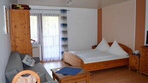 Une pièce comprenant un lit, un canapé, une armoire en bois et une petite table.