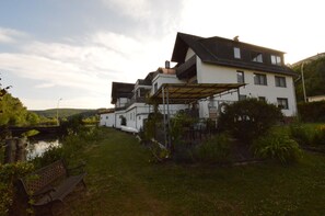 Ein zweistöckiges Haus mit überdachter Terrasse und kleinem Garten.