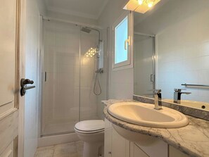A bathroom with a shower, toilet, sink, and a mirror.