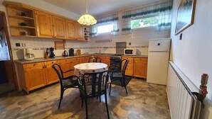 A kitchen with wooden cabinets, a dining table with chairs, a microwave, and a refrigerator.
