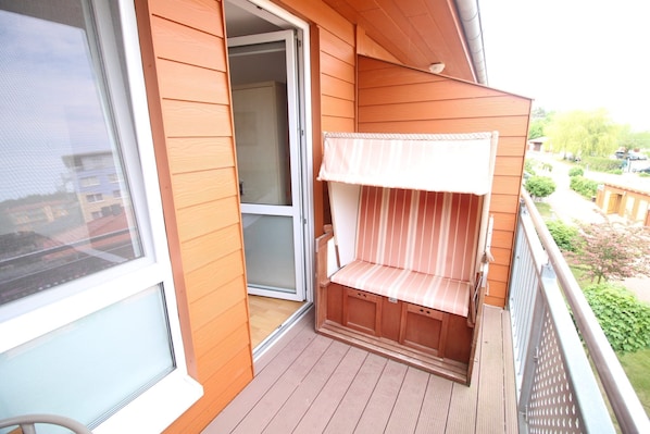 A wooden balcony with a sliding glass door, a cushioned bench, and a view of the neighborhood. - Zempin Ostseepark WE 30 Insel Usedom only 150m to the beach - WE 30 Strandläufer (Zempin)