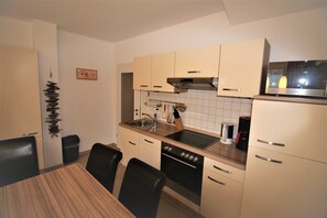 A compact kitchen with a dining table, chairs, a stove, oven, sink, and cabinets.