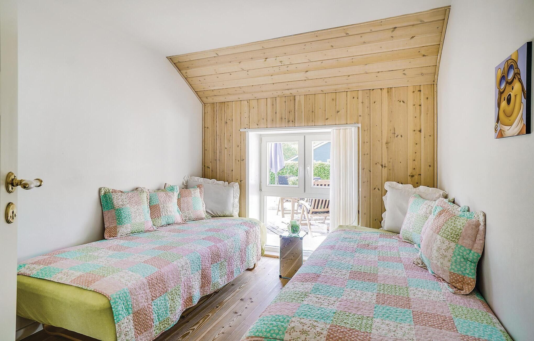 A bedroom with two beds, wooden ceiling, and a window with a view of the outside.