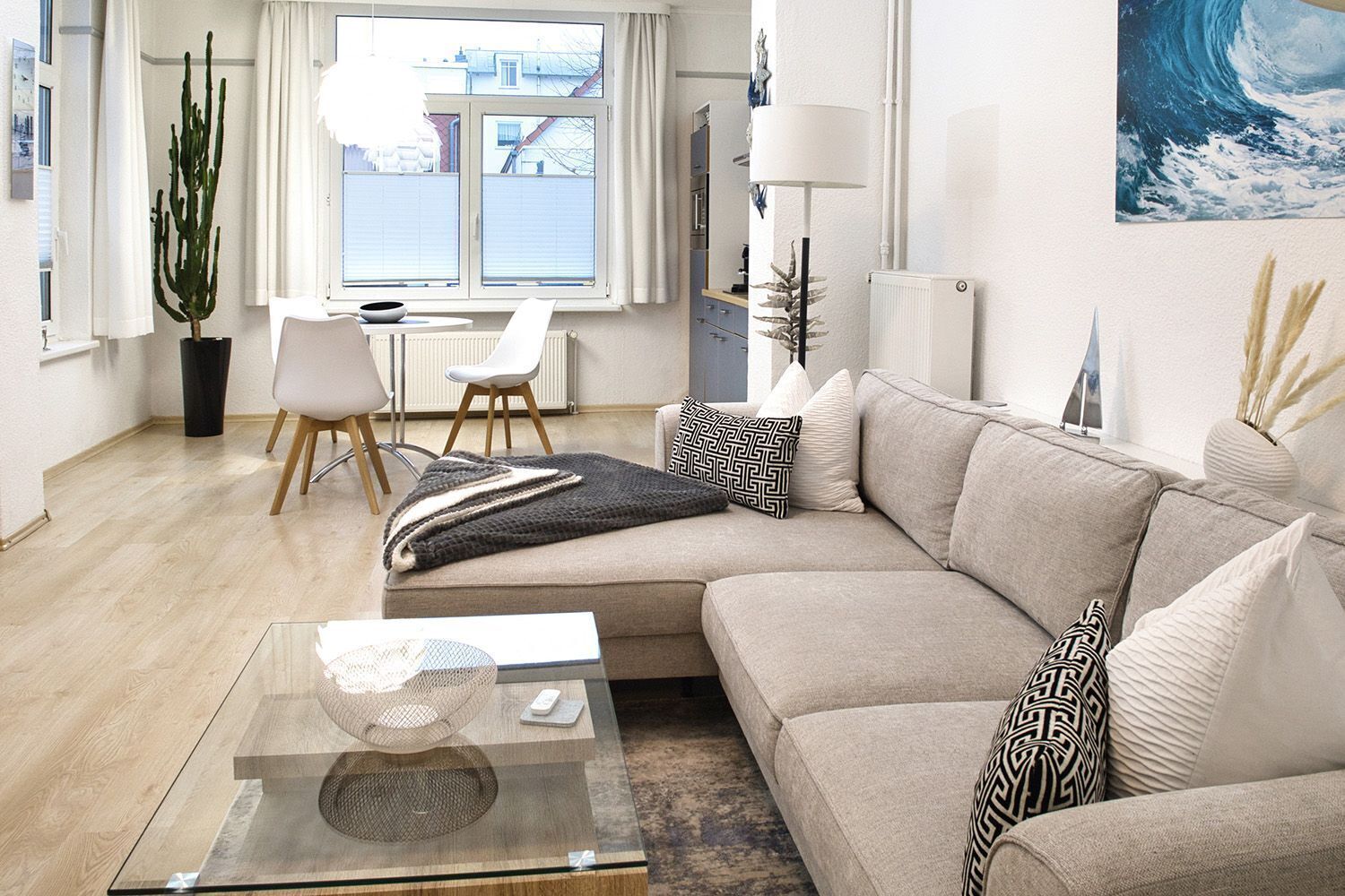 Un soggiorno moderno con un divano modulare beige, un tavolino in vetro e vista all'esterno attraverso un'ampia finestra.