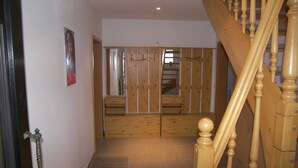 Una escalera de madera que lleva a una habitación con armario empotrado y espejo.