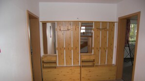Vestidor con puertas de madera, paneles espejos y estantes empotrados.