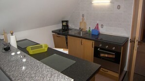 Una cocina compacta con encimera de granito, cafetera, tabla de cortar y horno pequeño.