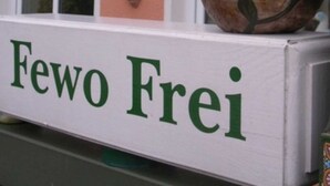 Un letrero con el texto 'Fewo Frei' y una estatua de una rana encima.