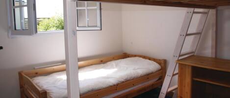 A small, single-bed room with a wooden bunk bed structure, a window, and a ladder.