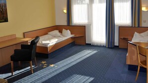 Una habitación de hotel con una cama, un escritorio, una silla y una ventana con cortinas.