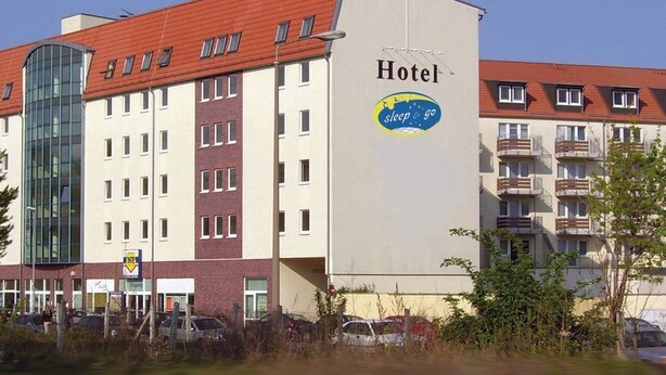 Un edificio de hotel con un cartel que dice "Hotel sleep & go" y una entrada de vidrio.