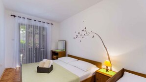 A hotel room with a bed, bedside table, lamp, and a wall decoration. - Holiday apartment with terrace (Crikvenica)