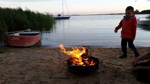 A beach scene with a campfire, a red boat named 'Lady', and a sailboat in the background.