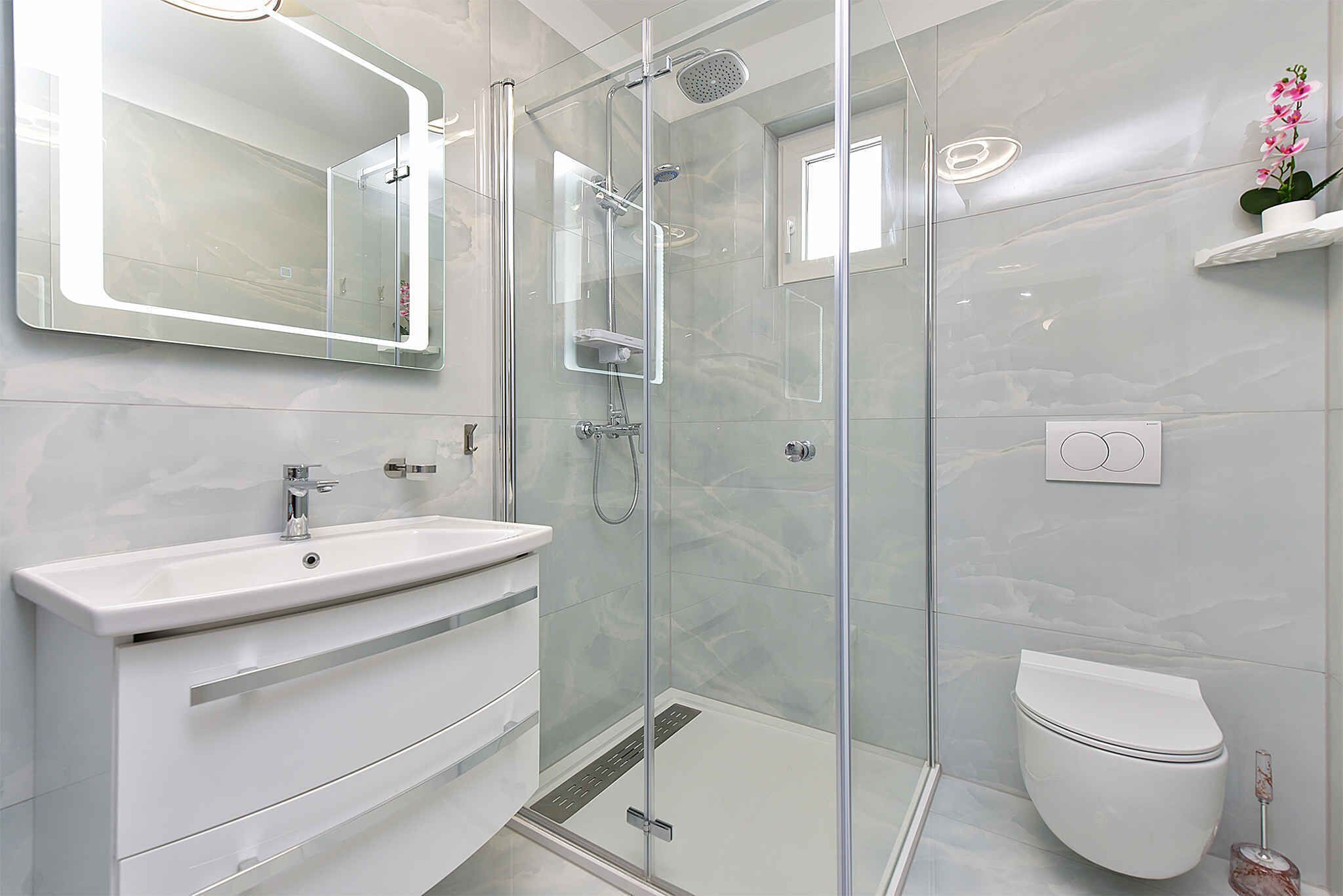 Un bagno moderno con doccia vetro, lavandino bianco e WC.