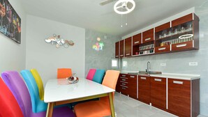A modern kitchen with wooden cabinets, a white countertop, and a dining area with colorful chairs. - Holiday apartment mit Klimaanlage und Terrasse (Fažana)
