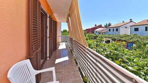 A balcony with a white chair, a railing, and a view of neighboring buildings and greenery. - Holiday apartment mit Klimaanlage und Terrasse (Fažana)