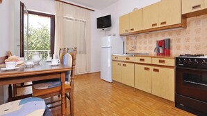 A compact kitchen with wooden cabinets, a built-in oven, and a refrigerator. - Nice apartment in Starigrad Paklenica (Starigrad Paklenica)