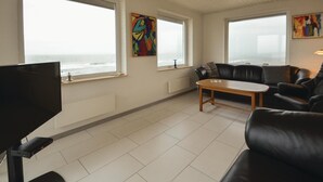 A living room with a TV, a sofa, a coffee table, and two windows with artwork. - Lovely home in Frøstrup with sauna (Frøstrup)