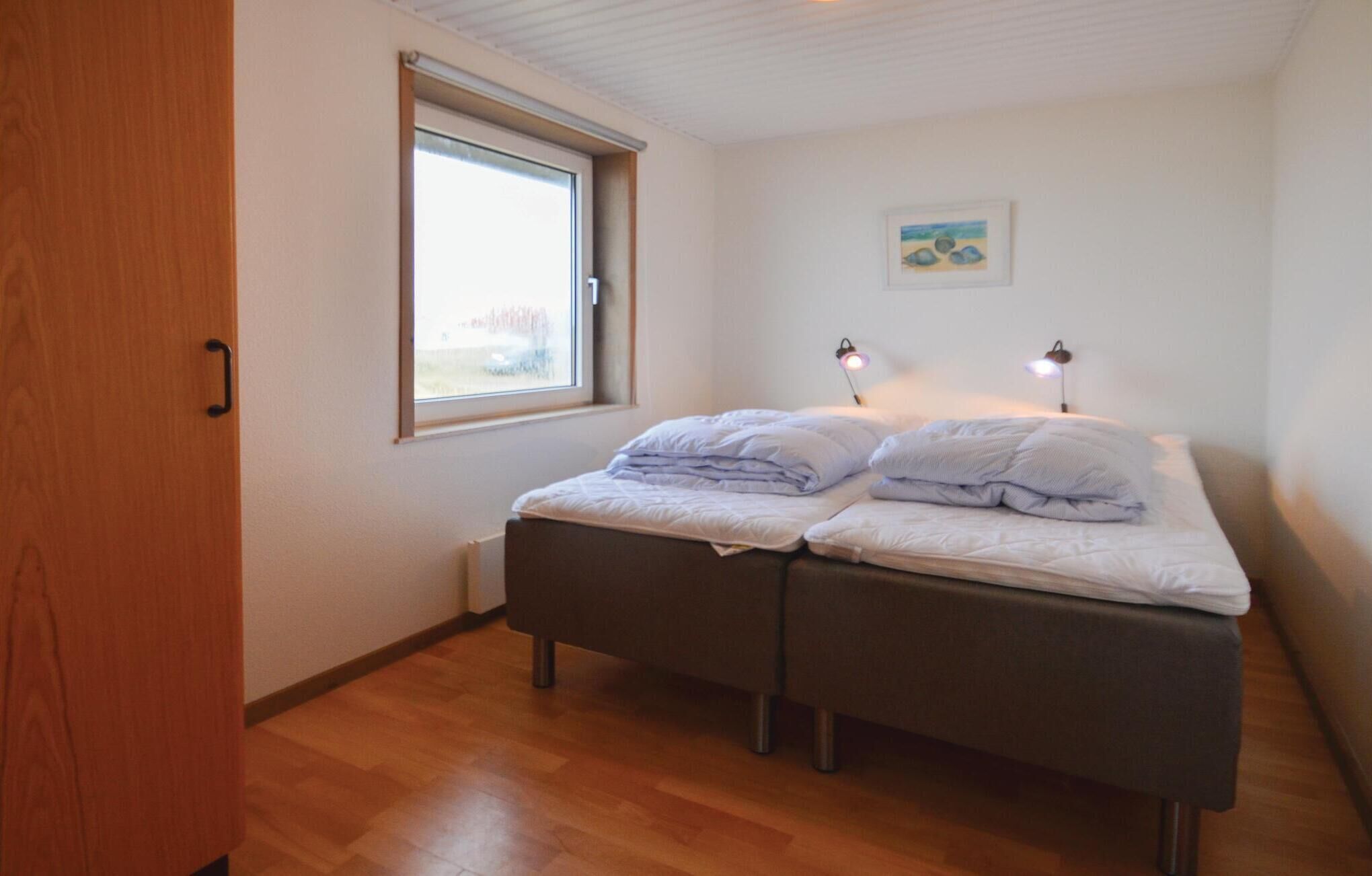Ein Schlafzimmer mit einem Doppelbett, einem Fenster und zwei Nachttischlampen.