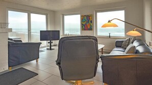 A modern living room with a large TV, comfortable seating, and a view of the ocean. - Lovely home in Frøstrup with sauna (Frøstrup)
