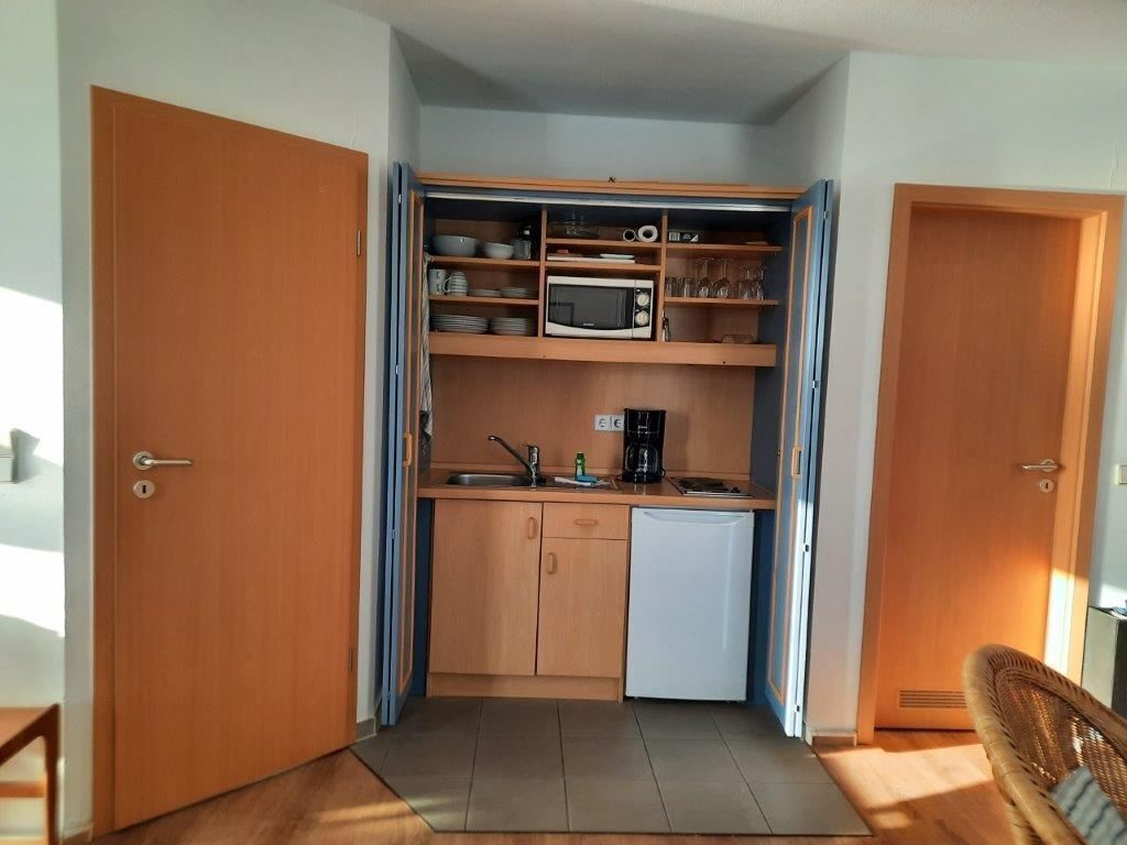 Una cocina compacta equipada con microondas, cafetera y un lavamanos pequeño.