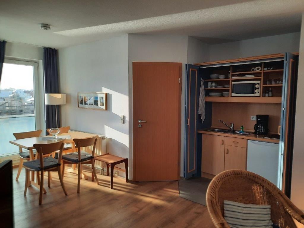 A compact living space with a dining area, kitchenette, and a view of the city.