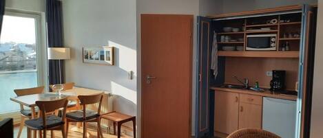 A compact living space with a dining area, kitchenette, and a view of the city.