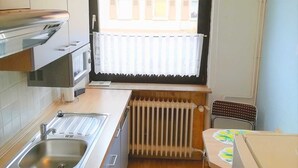 Et lille køkken med komfur, vask og køleskab.