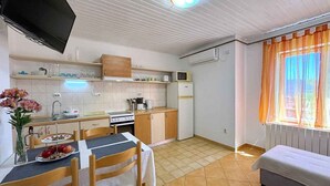 Eine kompakte Küche mit Esstisch, Stühlen, Fernseher und einem Bett.
